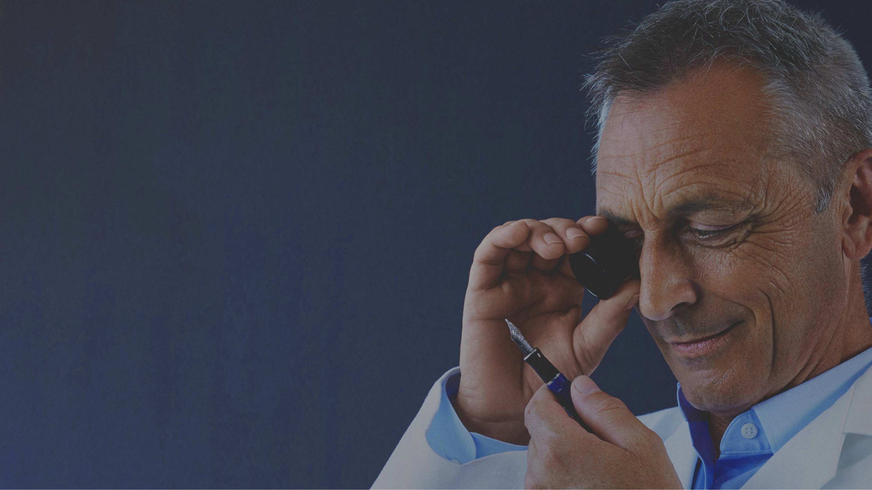 A pen expert using a monocular to study a fountain pen nib.